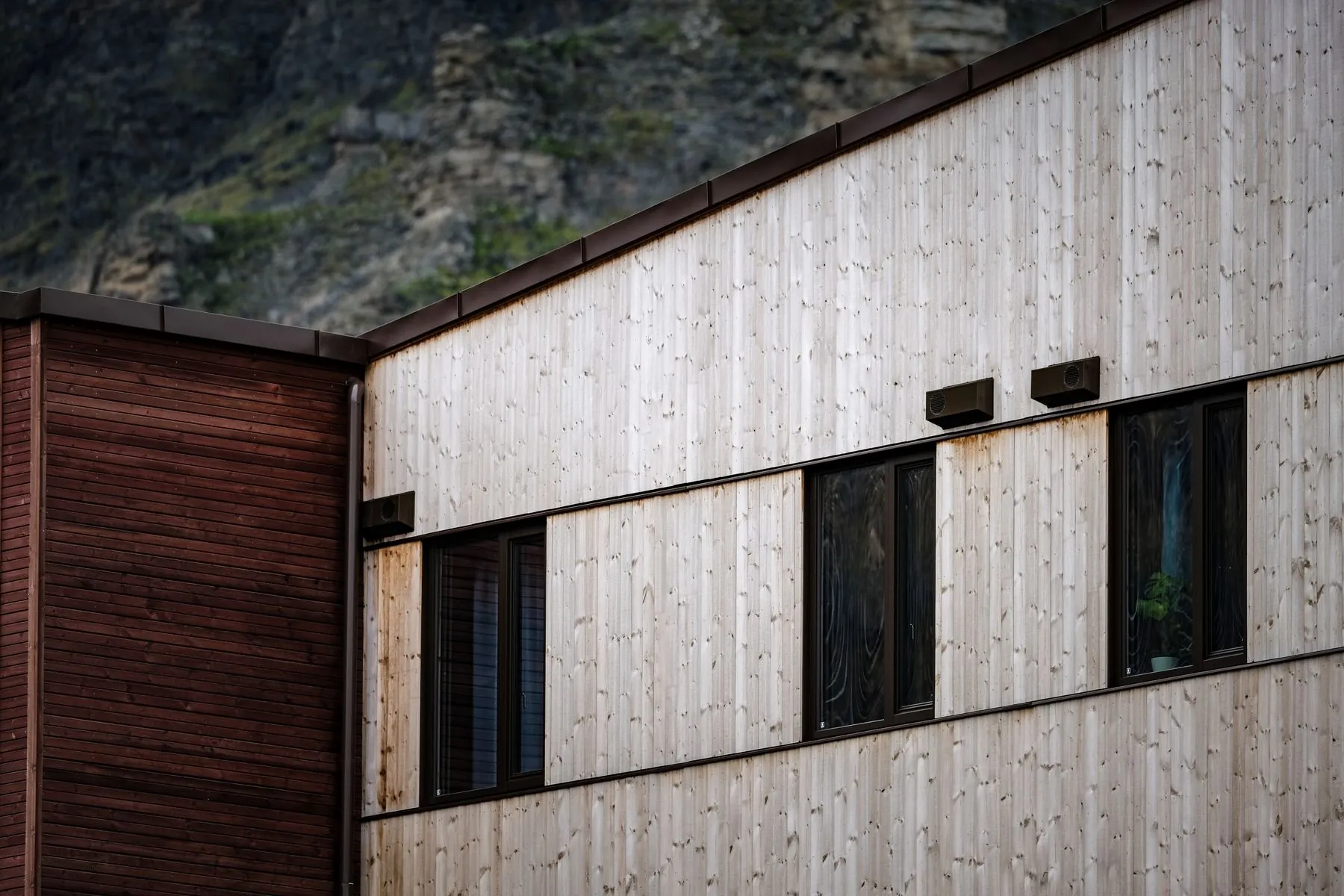 Close view of a building clad in pale timber boards with deep window reveals